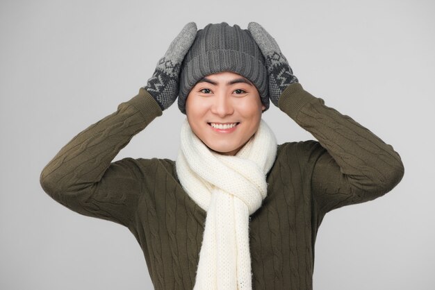 Young smiling asian man wearing knitted sweater and gloves