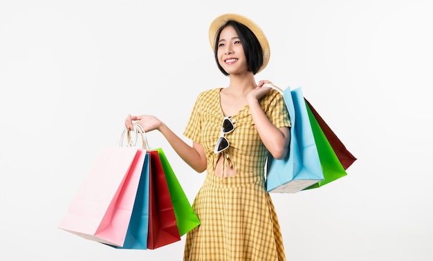 Young smiling asian woman holding multi coloured shopping bags and looking on white background.