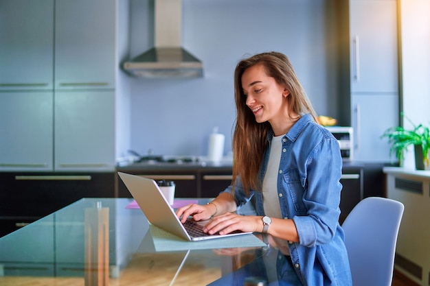 Giovane, sorridente, attraente, felice, adulto, carino, ragazza millenaria, freelancer, remoto, che lavora online su laptop a casa