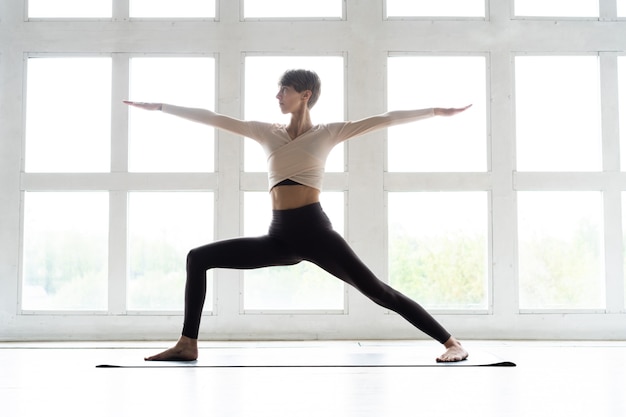 Giovane donna attraente sorridente che pratica yoga