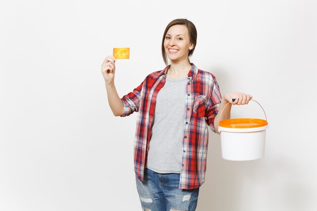 Young smiling beautiful woman in casual clothes holding credit card and empty paint bucket with copy space isolated on white background. Instruments for renovation apartment room. Repair home concept.