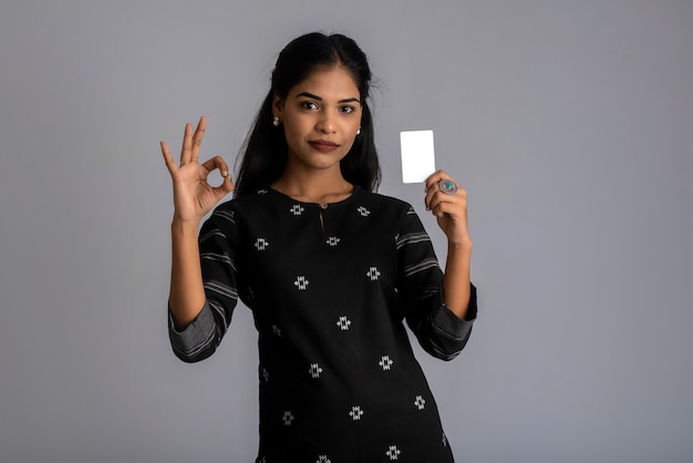 Young smiling beautiful woman or girl presenting credit card in hand showing trust and confidence for making payment.