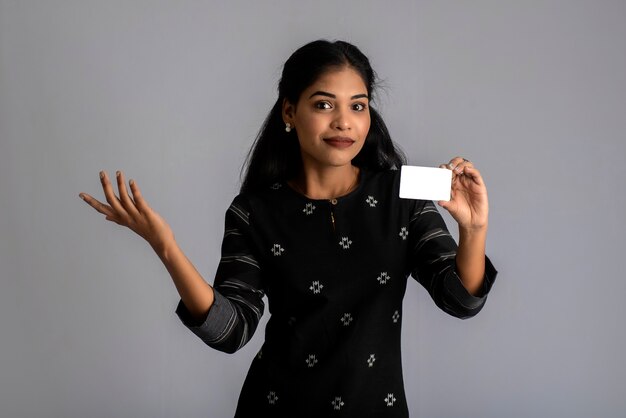 Young smiling beautiful woman or girl presenting credit card in hand showing trust and confidence for making payment.