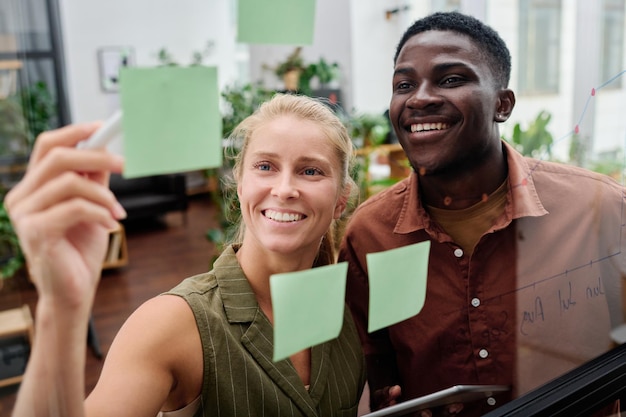 Photo young smiling blond female employee explaining her colleague working points