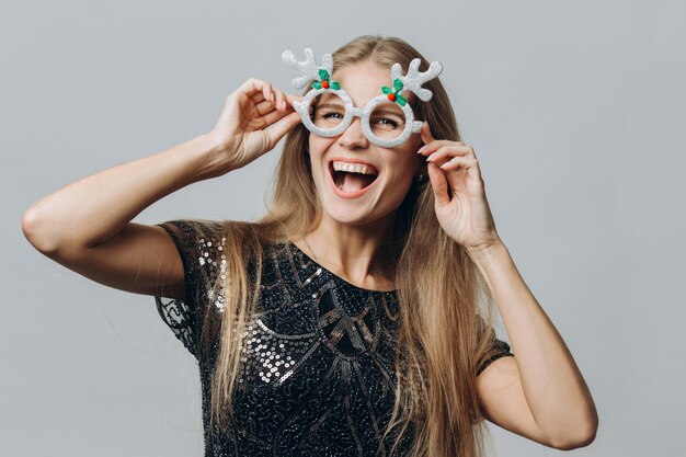 A young smiling blonde woman in glasses with deer antlers isolated on white background Christmas and New Year concept