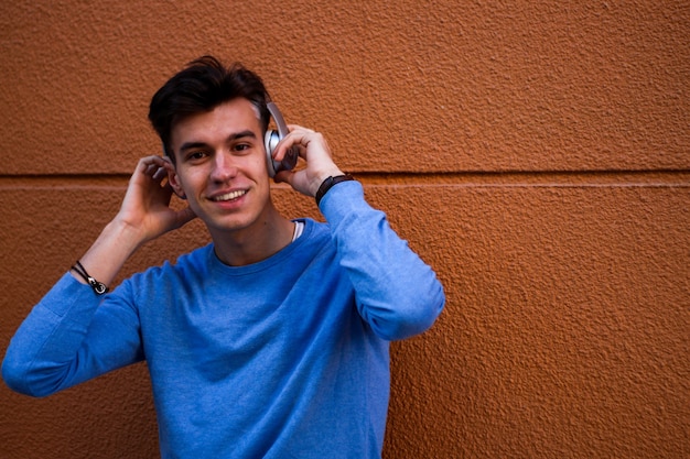 Young smiling boy with headphones on orange wall