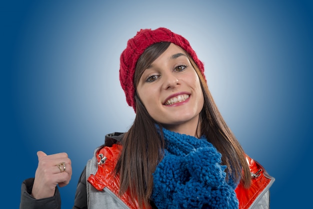 Young smiling brunette woman with a red winter cap