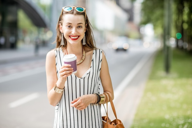 Young and smiling businesswoman having a coffee break standing outdoors on the street in Brussel city