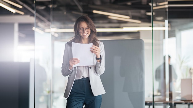 Young smiling businesswoman looking at the documents standing at office