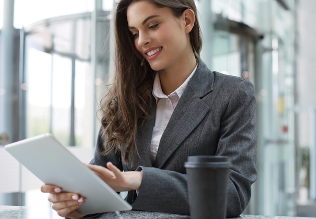 Young smiling businesswoman in office working on digital tablet.