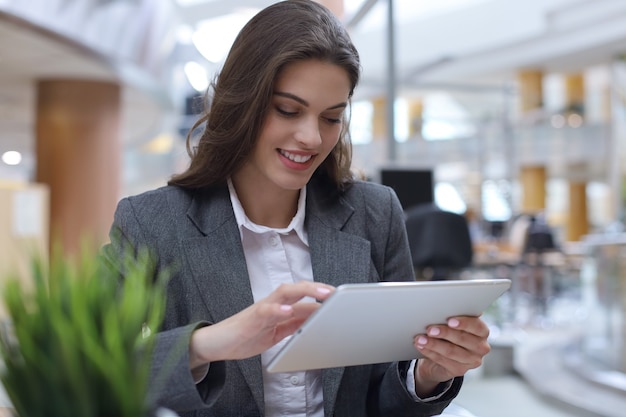 Young smiling businesswoman in office working on digital tablet.