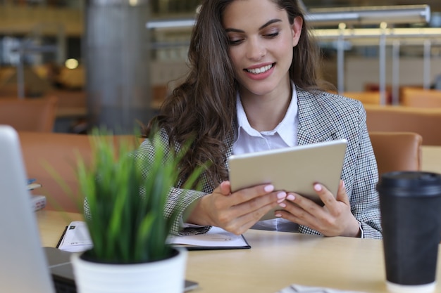 Young smiling businesswoman in office working on digital tablet.