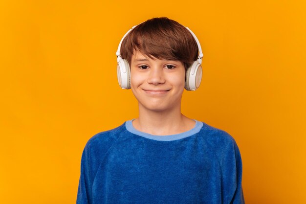 Young smiling at camera teen boy is wearing headphones and enjoying music