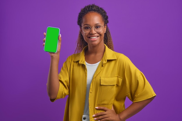 Young smiling casual african american woman demonstrates phone with green screen