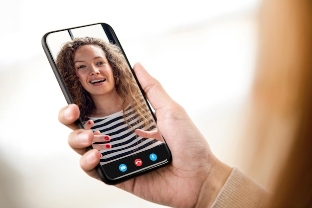 Young smiling caucasian woman having video call with friend on mobile phone