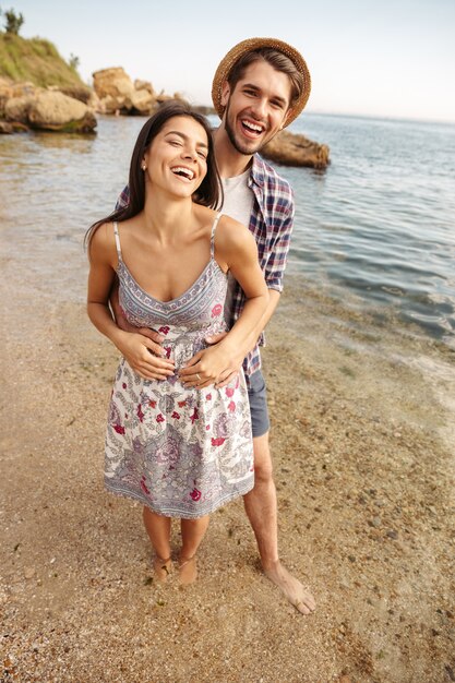 Young smiling couple in love standing at the beach and hugging