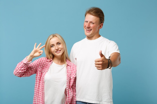 Young smiling couple two friend guy girl in white pink empty blank design t-shirts posing 