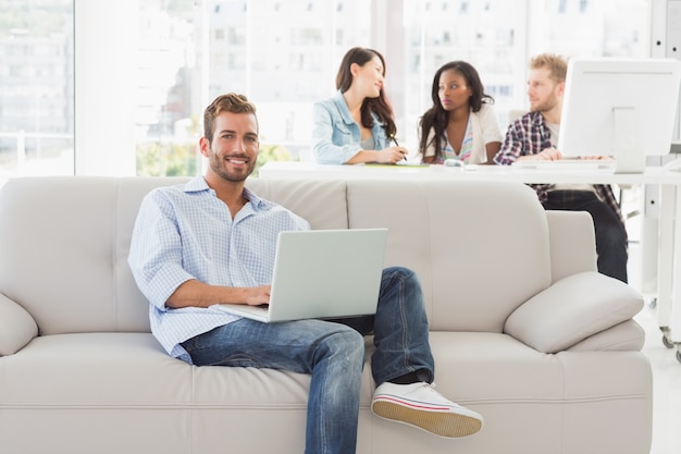 Young smiling designer working on his laptop on the couch