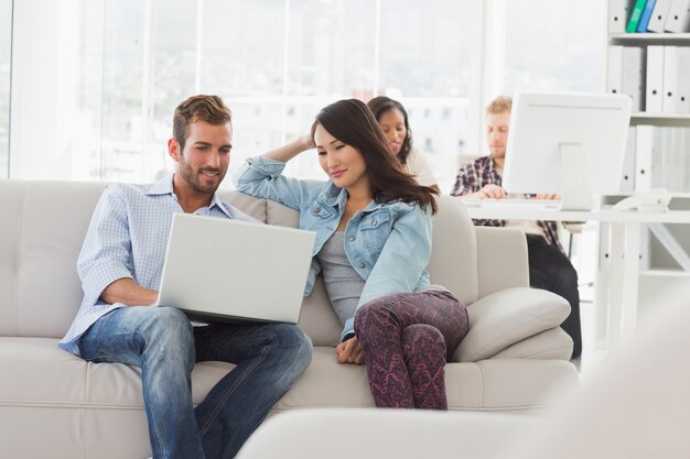 Young smiling designers working on laptop on the couch