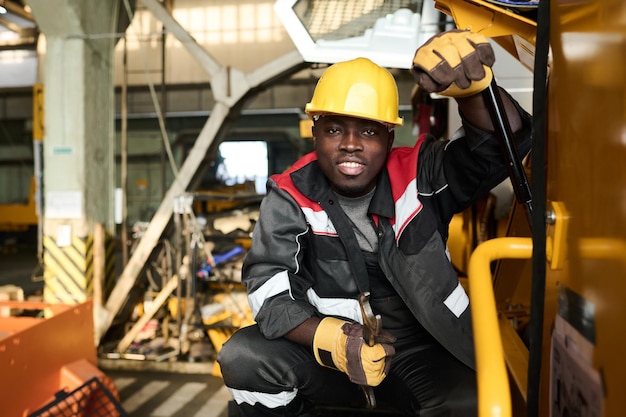 Young smiling engineer or repairman sitting on squats by machine