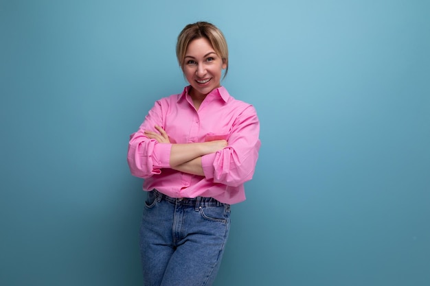 Young smiling european blond office worker woman dressed in a pink shirt and jeans