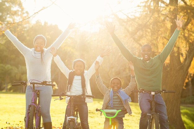 Young smiling family doing a bike ride with arms raised