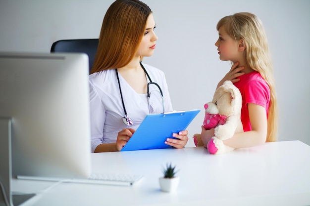 Young smiling female doctor and her little patient with teddy bear.