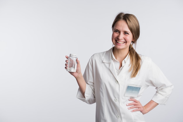 Young smiling female doctor presenting a white unlabeled bottle or recipient of pills