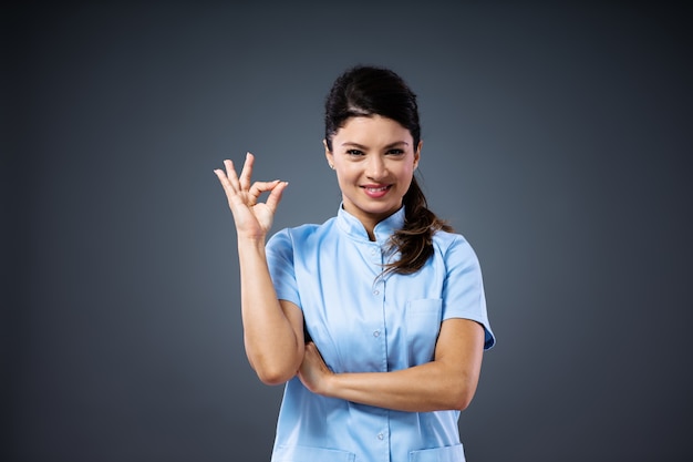 Photo young smiling female doctor standing and showing okay sign