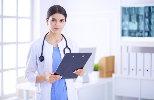 Young smiling female doctor with stethoscope holding a folder at doctor's office