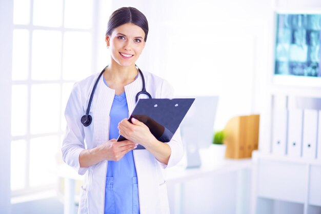 Young smiling female doctor with stethoscope holding a folder at doctor's office