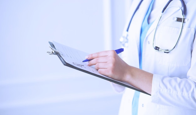 Young smiling female doctor with stethoscope holding a folder at a hospital's consulting room