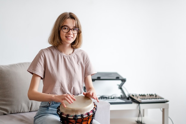 Young smiling female learning how to play djembe at home