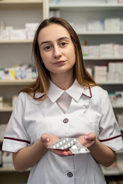 Young smiling female pharmacist marking an assortment of drugs in a pharmacy