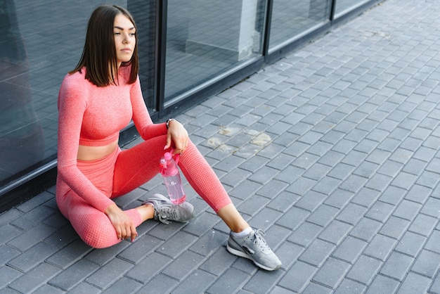 Giovane femmina sorridente che riposa dopo un allenamento fitness attivo.