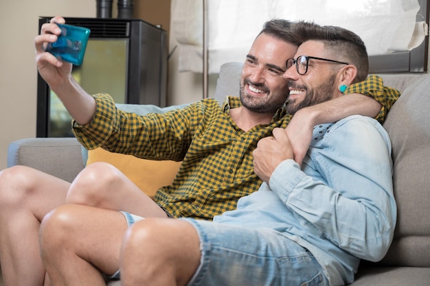 Foto giovani coppie gay sorridenti che prendono selfie a casa