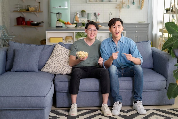 Young smiling gay couple watching tv in the living room at home\
lgbtq and diversity