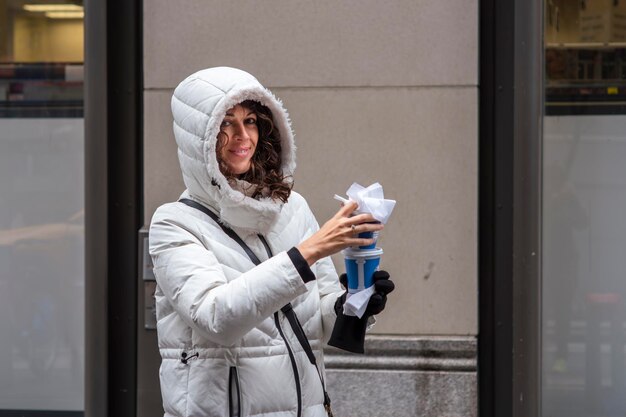 笑顔の若い女の子が路上で朝のコーヒーを運ぶ