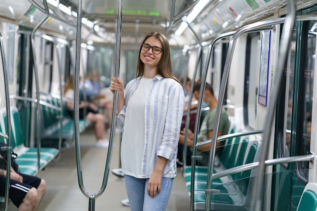 Young smiling girl inside subway car hold on handrail cheerful student female travel in underground