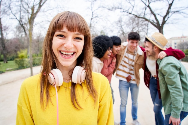 友達のグループと一緒に外でカメラを見ている笑顔の若い女の子楽しんでいる幸せな人々