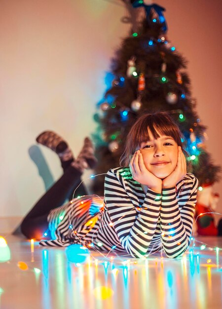 Young smiling girl lying before Christmas Tree