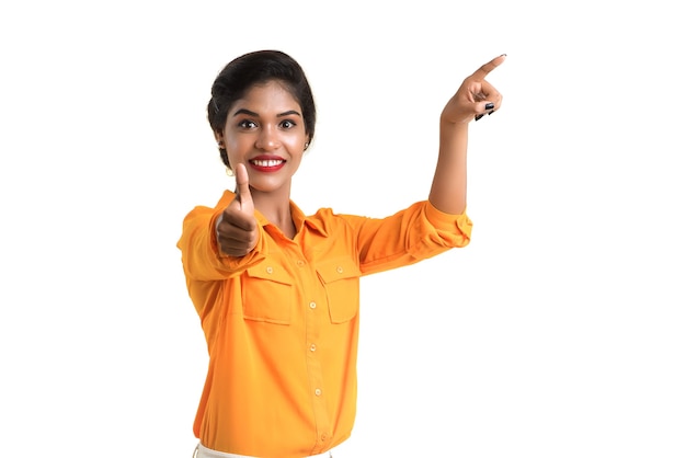 Young smiling girl pointing fingers to copy space on a white