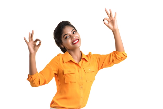 Young smiling girl showing ok sign or thumbs up on a white background