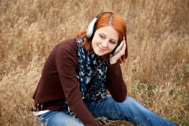 Young  smiling girl with headphones at field.