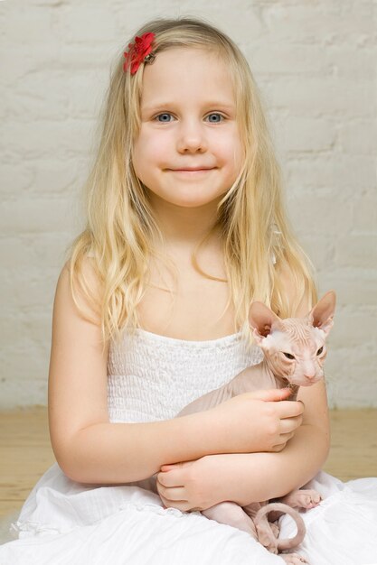 Photo young smiling girl with kitten sphinx