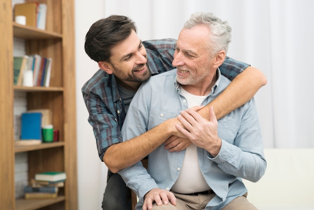 Young smiling guy hugging aged man