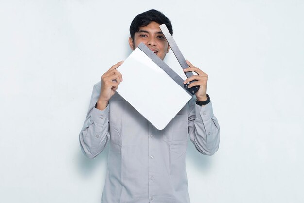 Young smiling happy asian man holding white film making clapperboard isolated on white background