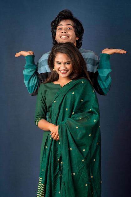 A young smiling happy couple standing together presenting something in their hand on a gray background