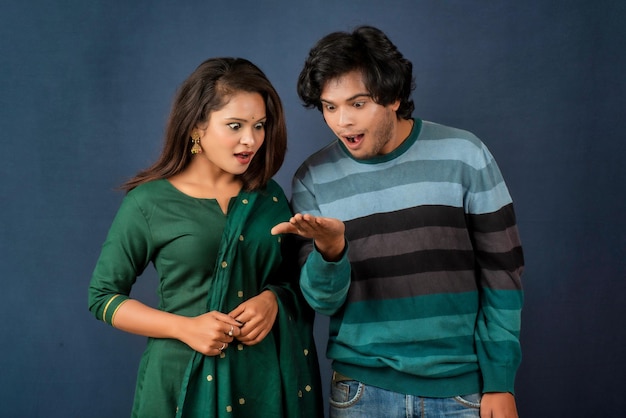 A young smiling happy couple standing together presenting something in their hand on a gray background