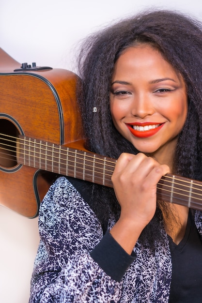 young smiling Hispanic female posing at the camera holding a guitar on her shoulder